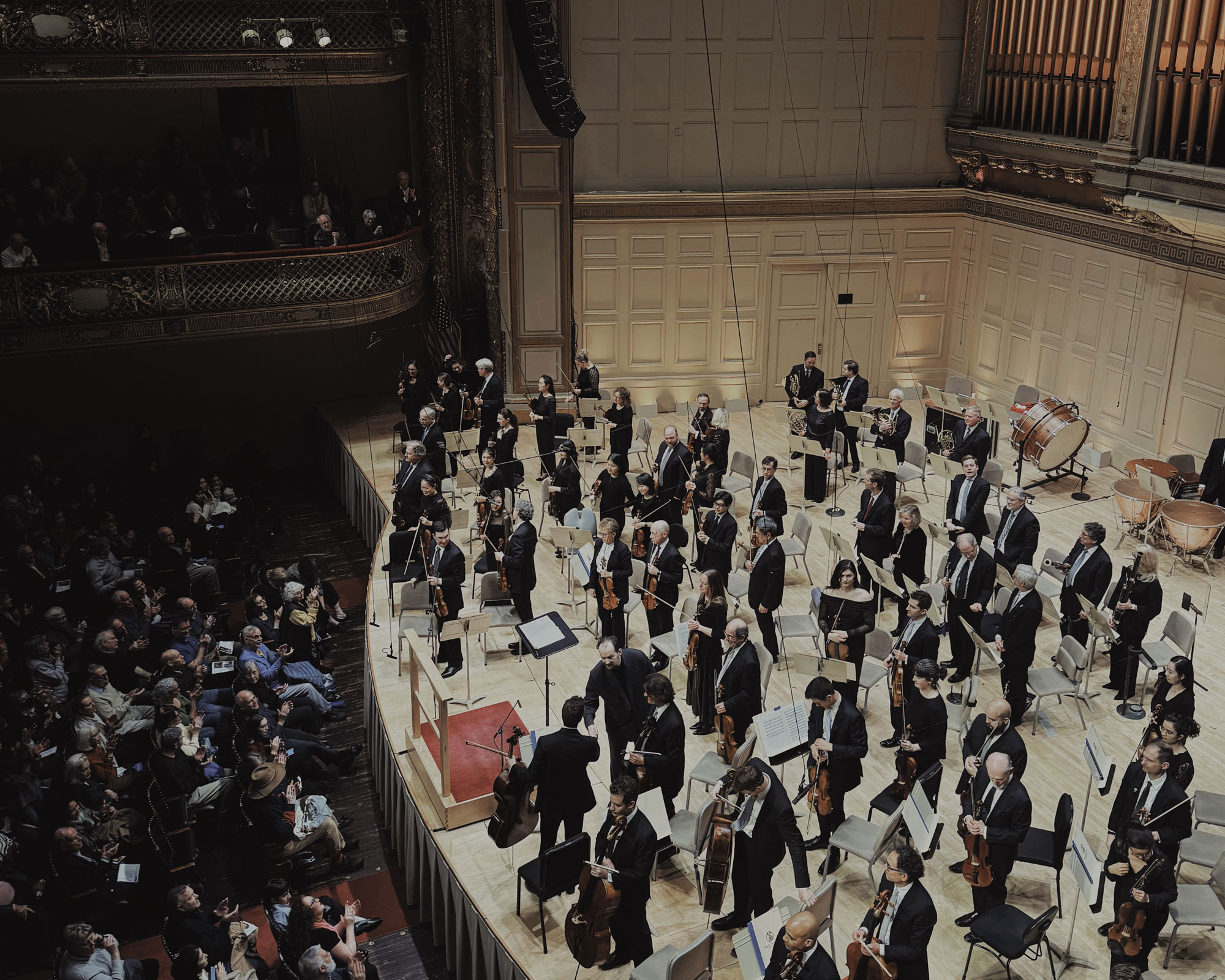 Symphony Hall でのBoston Symphony Orchestra 終演後の舞台上の写真。中央で指揮者であるアンドリス・ネルソンスが、オーケストラのメンバーと握手している。